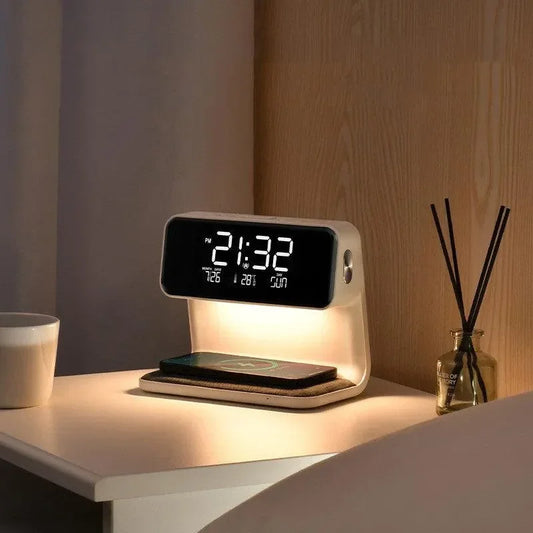 Modern digital alarm clock with wireless charging pad on bedside table with diffuser and cup