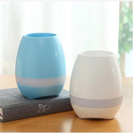 Two modern plastic smart cups, one blue and one white, on a wooden table indoors
