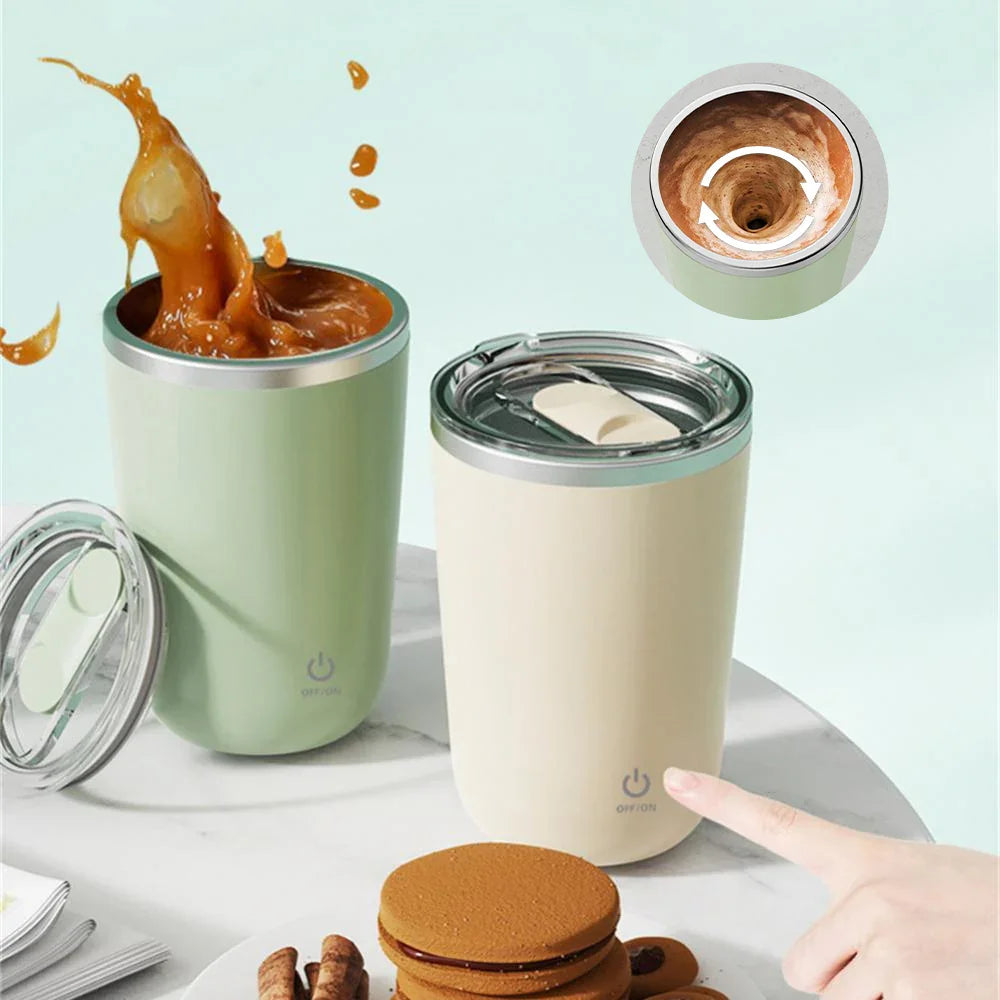 Electric self-stirring mugs with lids, one mixing coffee, on a marble table with cookies.