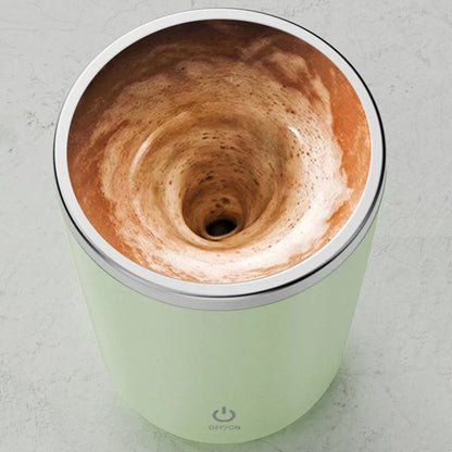Automatic electric frother mug mixing coffee with foam swirl on a countertop