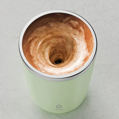 Electric self-stirring mug mixing coffee on a countertop, power button visible on the cup.
