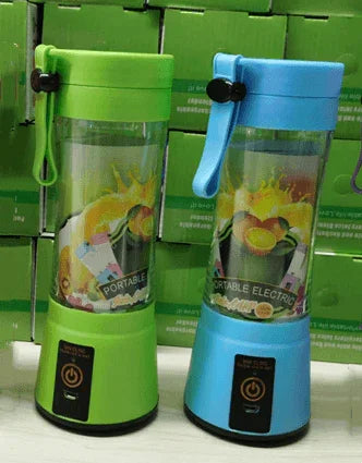 Green and blue portable electric blenders with fruit graphic on transparent bodies, set against green boxes